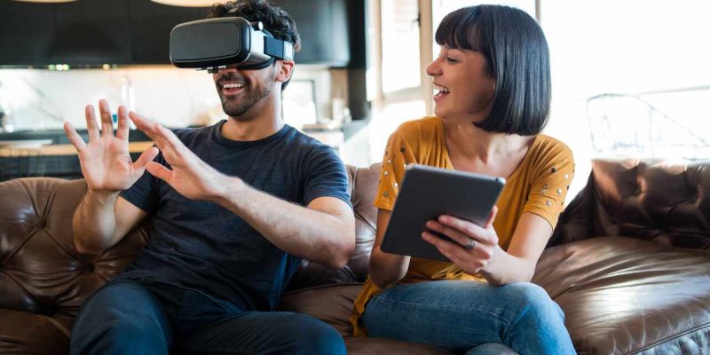 Couple playing video games with VR glasses. Portrait of young couple having fun together and playing video games with VR glasses while staying at home. New normal lifestyle concept.